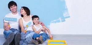 Young couple painting their walls blue with their young son