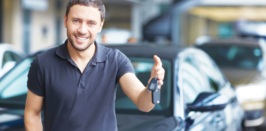 Man in polo shirt holding out car keys