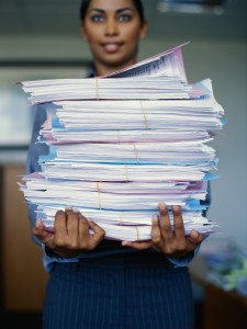 business woman holding large stack of files