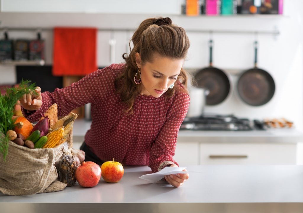 woman looking at receipt with groceries on table