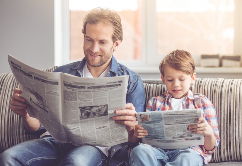 father and son reading newspaper