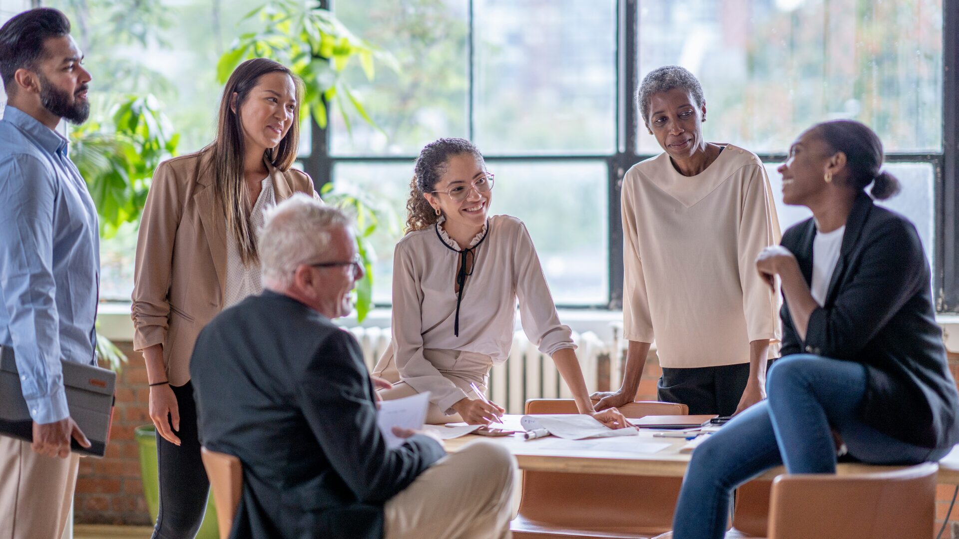 a group of people, varied ages and races, together at a table, having a casual meeting