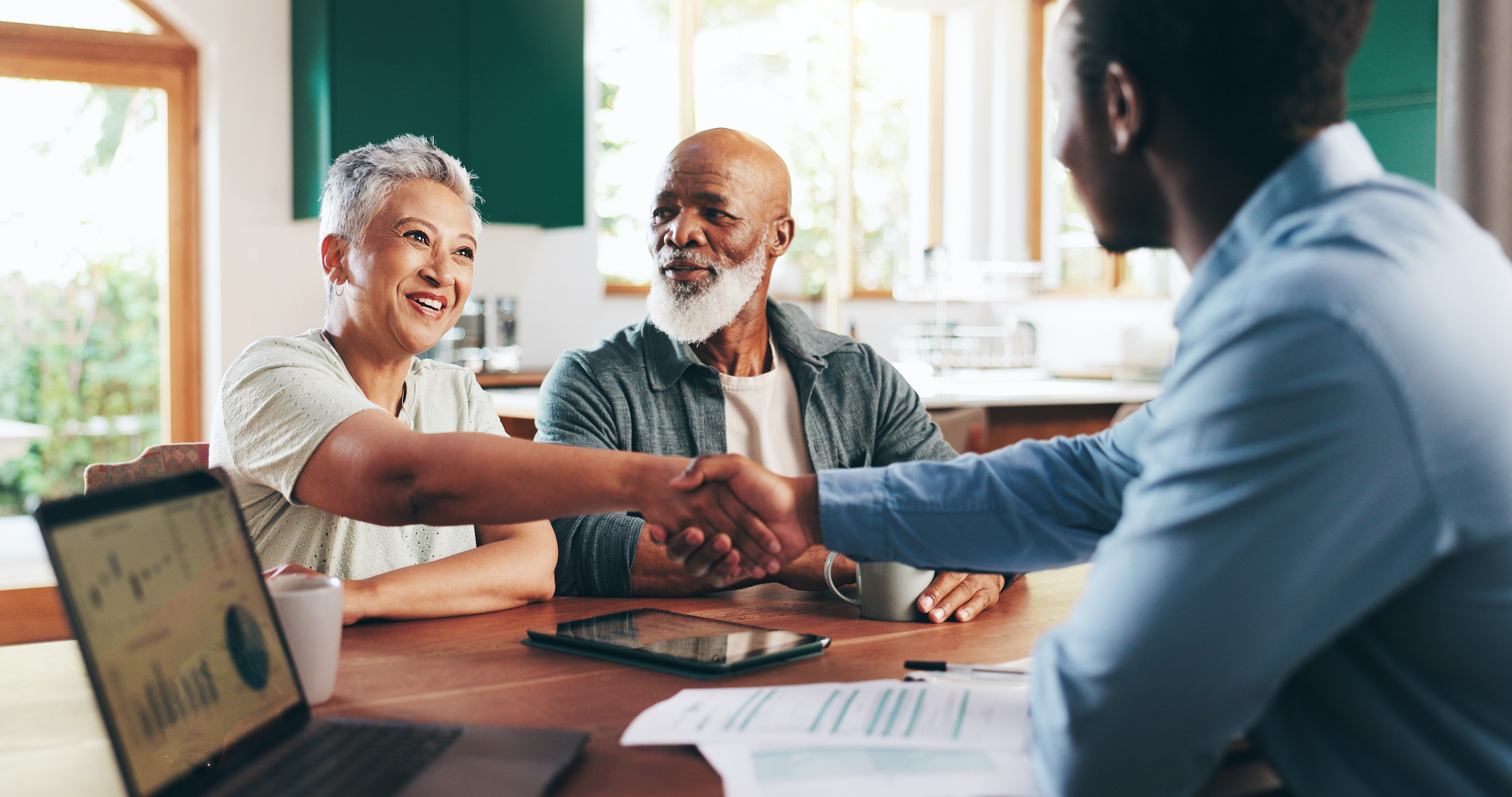 A couple sits across a desk from someone who works at a bank and discussing their retirement options.