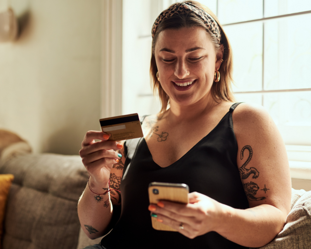 Untitled design (1) woman looking at phone and bank card